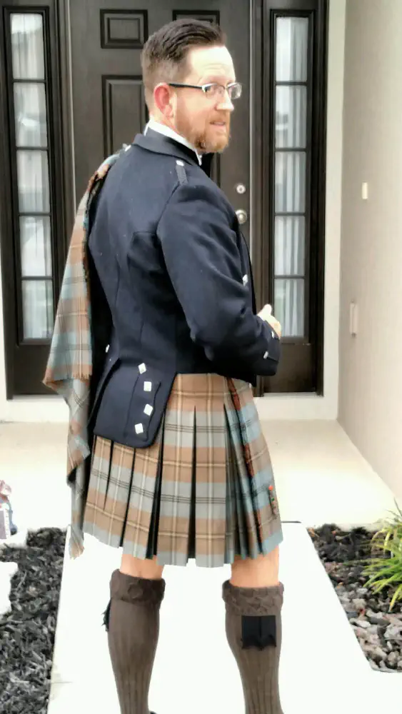 A tartan kilt and matching plaid worn with a dark Highland jacket.